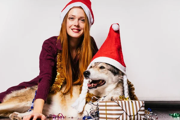 快乐的女人在新年的帽子旁边坐着一条狗 — 图库照片