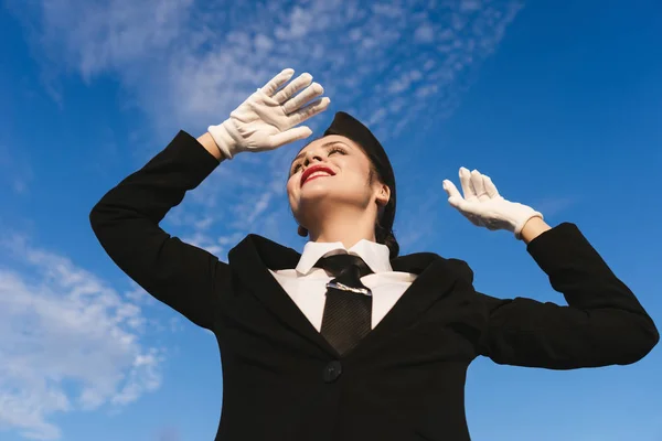 Femme heureuse hôtesse de l'air en uniforme posant à la caméra sur fond de ciel Photos De Stock Libres De Droits