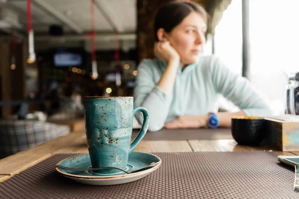 La mujer está sentada en un café a la mesa —  Fotos de Stock