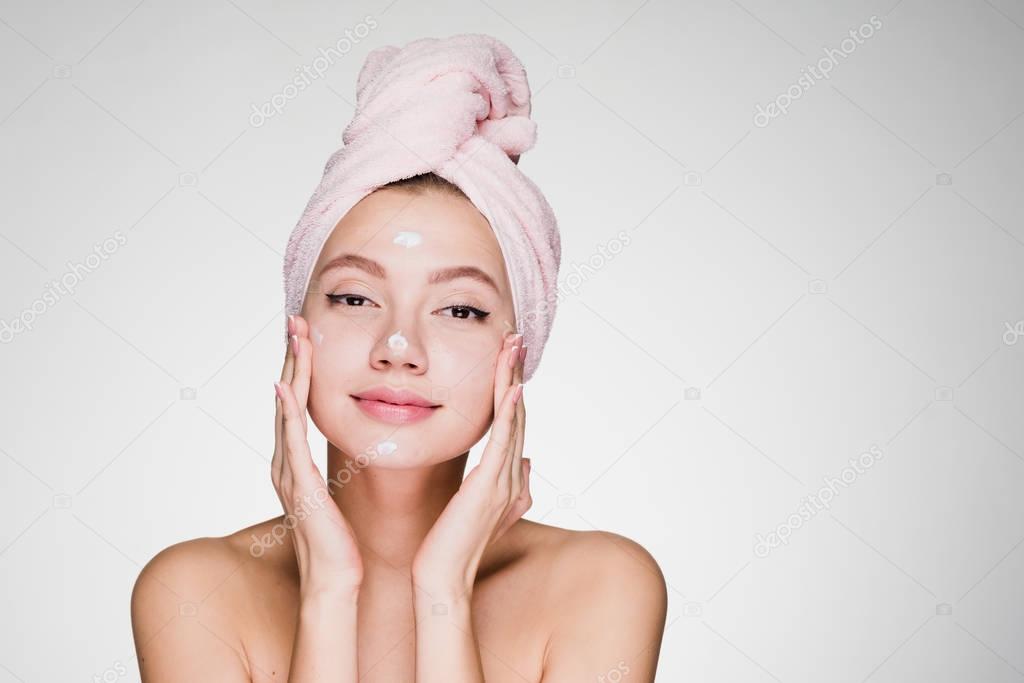 the amazed woman with a towel on her head after showering the cream on her face