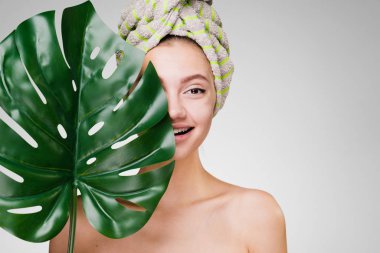 Kafasındaki bir havlu ile mutlu kadın elinde yeşil bir yaprak tutar.