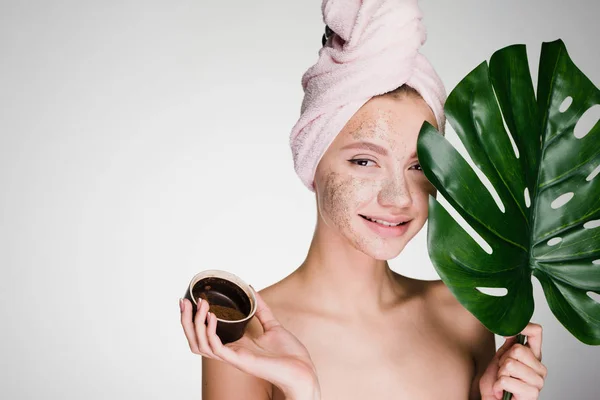 Mulher feliz com uma toalha na cabeça aplicou uma esfoliação em seu rosto — Fotografia de Stock