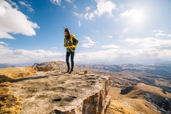 Donna turista è in piedi con uno zaino su uno sfondo di alta montagna — Foto Stock