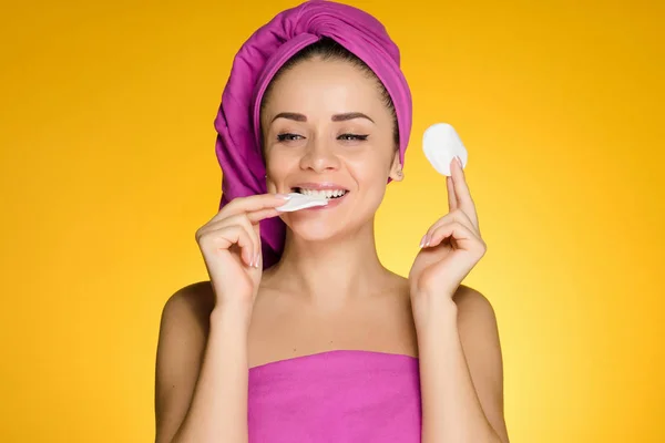 Mulher feliz com uma toalha na cabeça mordendo rodas acolchoadas — Fotografia de Stock