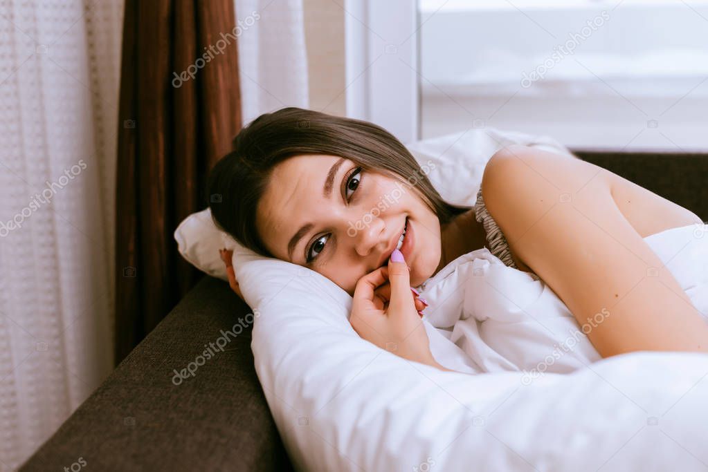 cute smiling girl lies in bed, early in the morning