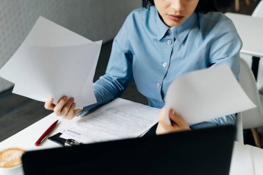 İş kadını ofisinde oturuyor ve belgeleri inceliyor.