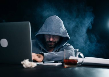 karanlık bir odada oturan bir kukuleta ile bir kazak erkek hacker