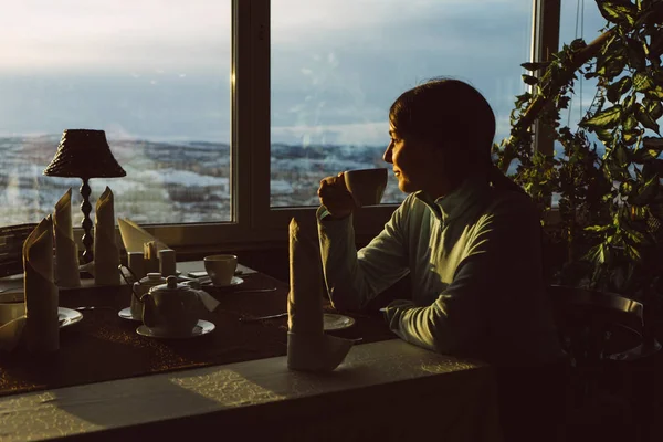 Mujer está bebiendo té en un café y mirando por la ventana —  Fotos de Stock