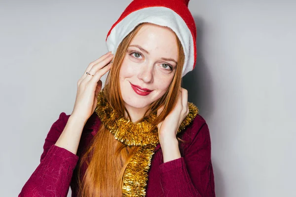 Glückliche Frau mit Weihnachtsmütze auf grauem Hintergrund — Stockfoto