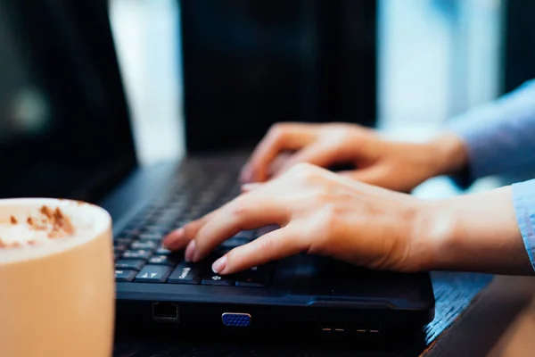 A mulher está sentada à mesa no escritório e o que está digitando — Fotografia de Stock