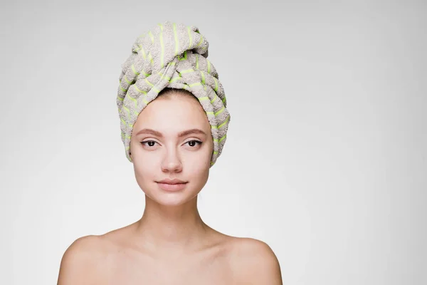 En förvånad kvinna med en handduk på huvudet poserar på kameran — Stockfoto