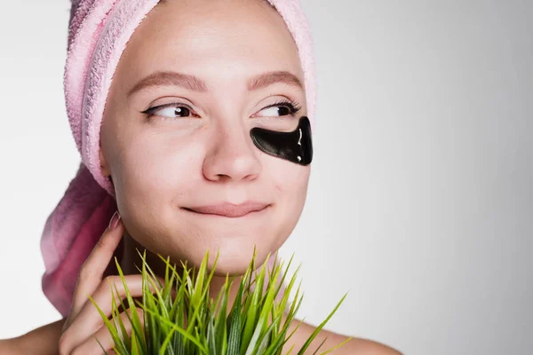 Happy woman with a towel on her head put patches under her eyes and looks away — Stock Photo, Image