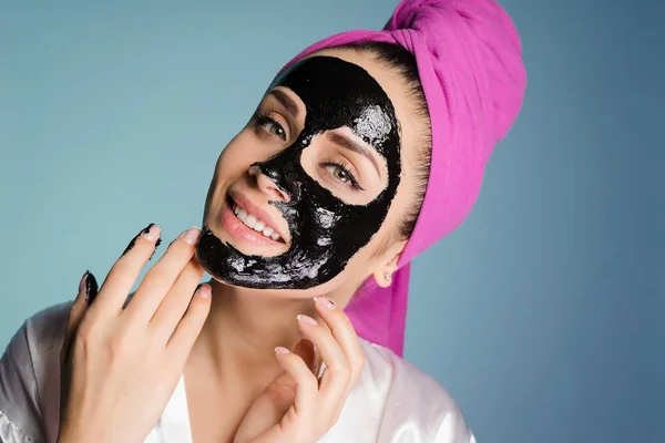 Boldog asszony, a fejét egy törülközővel alkalmazott tisztító maszk az arc bőrén — Stock Fotó