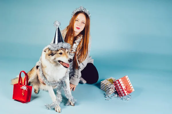 Una mujer en un sombrero festivo se sienta al lado de un perro grande — Foto de Stock