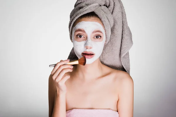 The amazed woman with a towel on her head apply a cleansing mask — Stock Photo, Image