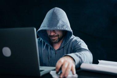 laptop görünümlü ve sonra yazmaya ve gülümseyen masada oturan adam hacker