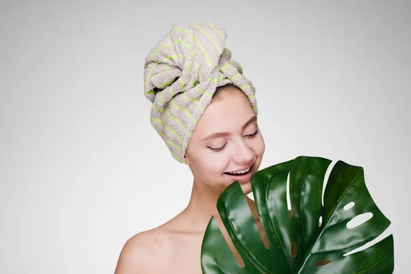 Šťastná žena s ručníkem na hlavě při pohledu na velký zelený list — Stock fotografie