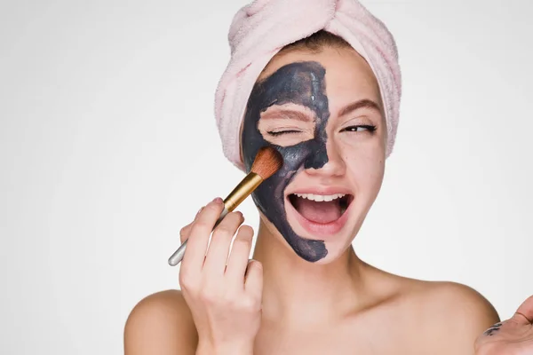 머리에 수건을 쓴 행복 한 여인이 얼굴을 닦는 마스크를 쓰고 있다 — 스톡 사진