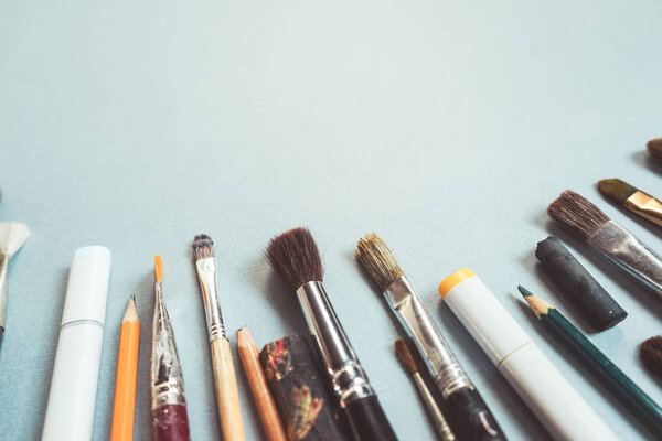 на синем фоне лежат маркеры, кисти
