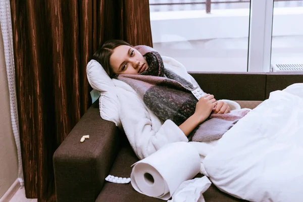 A sick woman lies on a bed amid medications — Stock Photo, Image