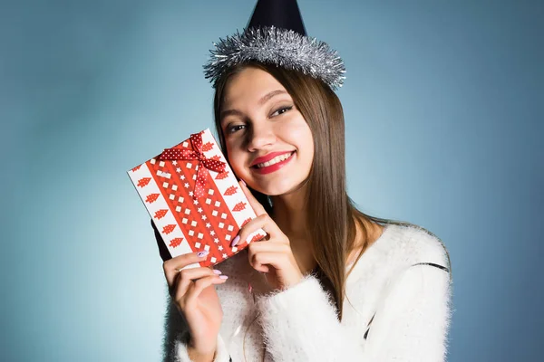Gelukkige vrouw in een feestelijke hoed houdt een geschenk in haar handen — Stockfoto