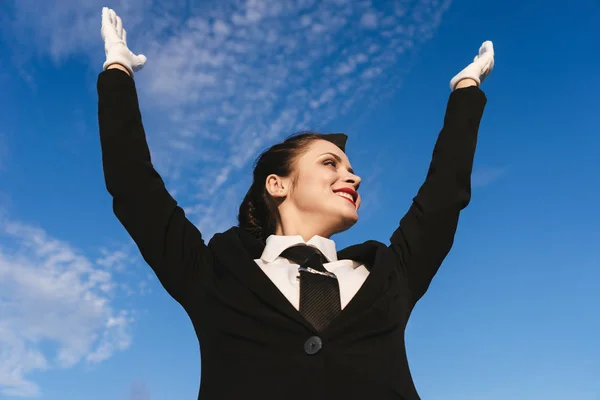 Glückliche weibliche Stewardess in Uniform hebt die Hände — Stockfoto