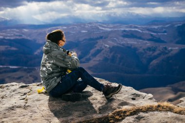 kadın turist yüksek dağlar bir arka plan üzerinde sıcak çay içer