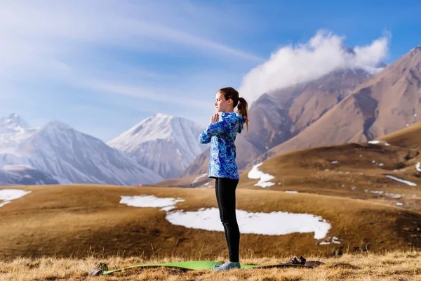 Женщина туристическая йога на фоне высоких гор — стоковое фото