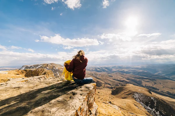 Жінка-турист сидить і тримає рюкзак на фоні високих гір — стокове фото