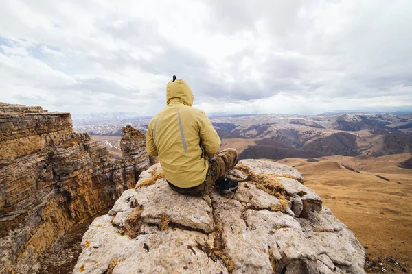 Male tourist is sitting on a background of high mountains — Stock Photo, Image