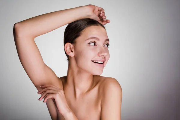 happy woman looks after armpit skin and looks away