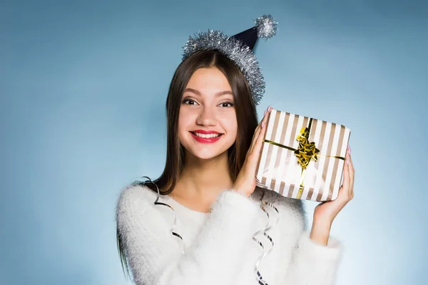 Gelukkig jong meisje met een pet op haar hoofd houdt een Nieuwjaars-gift — Stockfoto