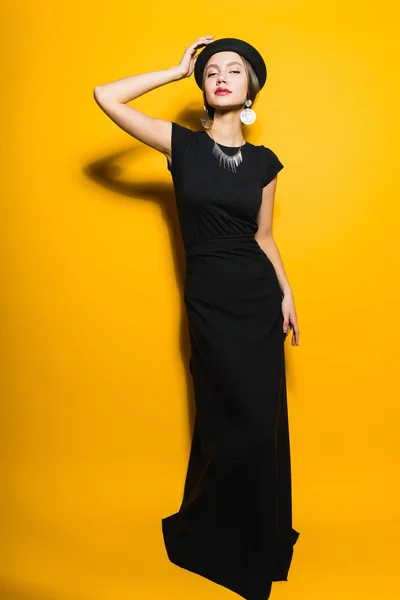 Rich elegant young woman posing in a long black dress and hat — Stock Photo, Image