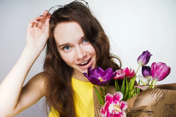Glad vacker ung flicka firar en kvinnlig dag, håller 8 mars, en bukett vackra doftande blommor — Stockfoto