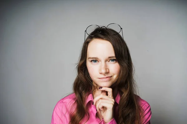 Bela jovem trabalhador de escritório menina em uma camisa rosa sorri e pensa em algo — Fotografia de Stock