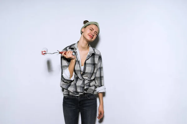 Sad young girl wants to make repairs in the apartment, holds a roller in her hands — Stock Photo, Image