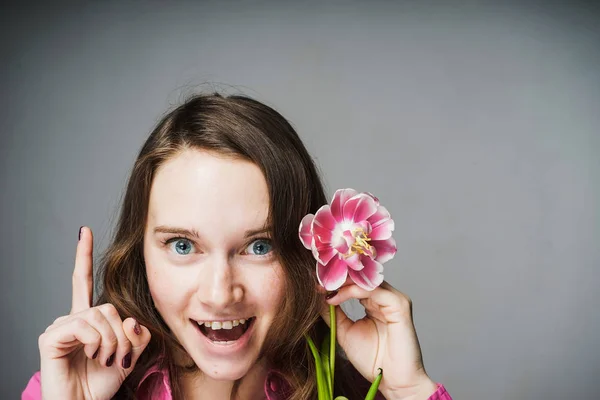 Divertente ragazza in camicia rosa è felice tenendo un fiore rosa — Foto Stock