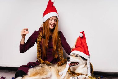kırmızı bere içinde mutlu Kızıl saçlı kız köpeğiyle yeni yıl kutluyor