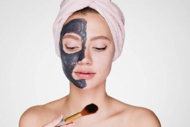 sevimli genç kız başında pembe havlu ile yüz kil maskesi koyar