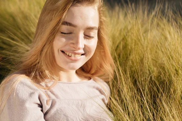 Счастливая молодая девушка лежит в поле, на солнце, улыбается — стоковое фото