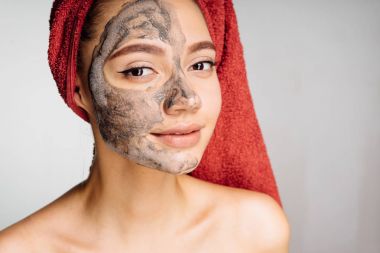 Kafasındaki bir havlu ile güzel güzel kız bir kil maskesi uygulanmış