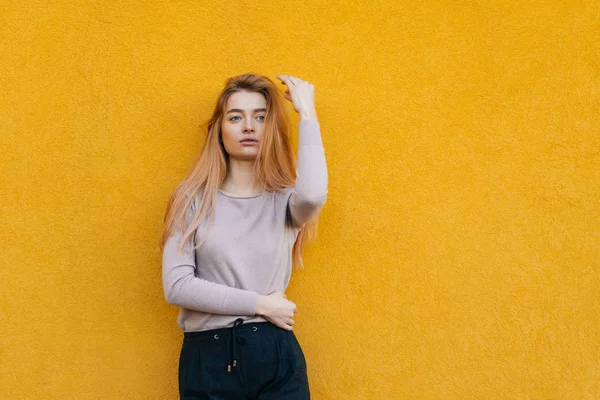 Cute young blonde girl posing on yellow background, street fashion — Stock Photo, Image