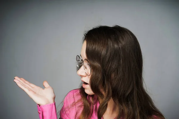 Удивленная молодая женщина в розовой рубашке и очках возмущена — стоковое фото