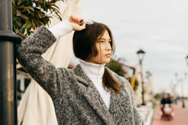 Jeune fille élégante avec les cheveux foncés et dans un manteau gris marchant dans les rues de la ville — Photo