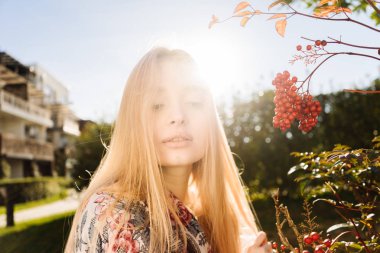 sevimli genç sarışın kız sıcak güneşli havalarda bahçede yürürken