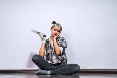 üzgün onarım yapıyor, katta oturan ve bir spatula tutan genç kız yorgun