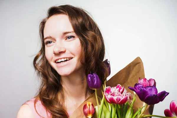 Feliz hermosa joven sosteniendo un gran ramo de flores, celebrando un día mundial de la mujer — Foto de Stock