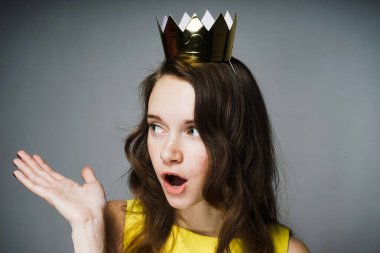 lovely surprised girl with a golden crown on her head asks a question clipart