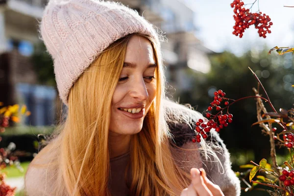 Felice bella ragazza bionda in cappello passeggiando in giardino, sorridendo, guardando le bacche — Foto Stock