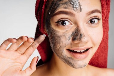 güzel genç kız güzel, yararlı kil maskesi yüz, gülümseme yarısı üzerinde koymak istiyor